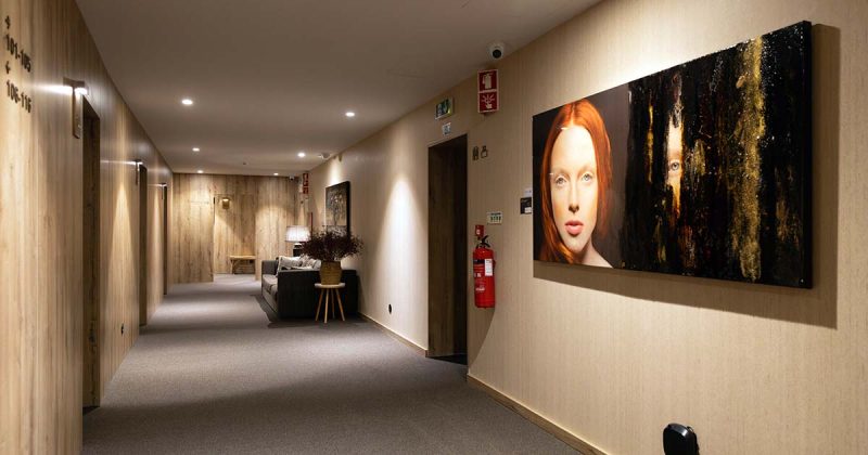 Interior da unidade hoteleira, com quadro em destaque no corredor dos quartos