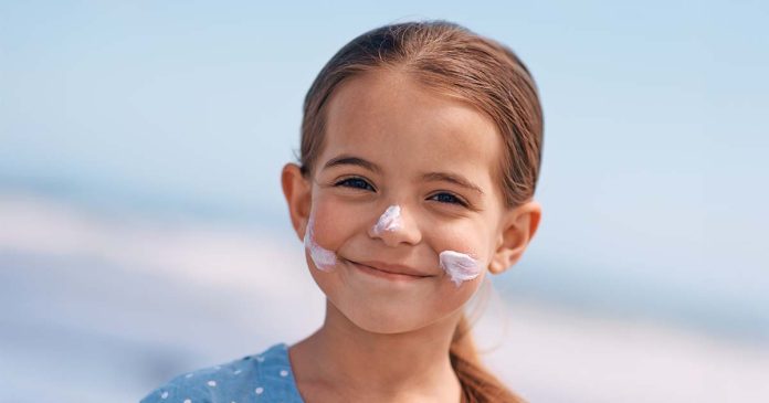 Proteção solar infantil ajuda a proteger a pele das crianças no verão Proteção solar infantil aplicada no rosto de uma criança durante um dia de verão para proteger a pele dos raios UV.