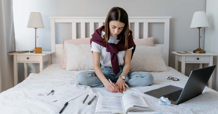 Estudante a estudar Alojamento estudantil associado à rotina de uma estudante que estuda num quarto com livros e computador