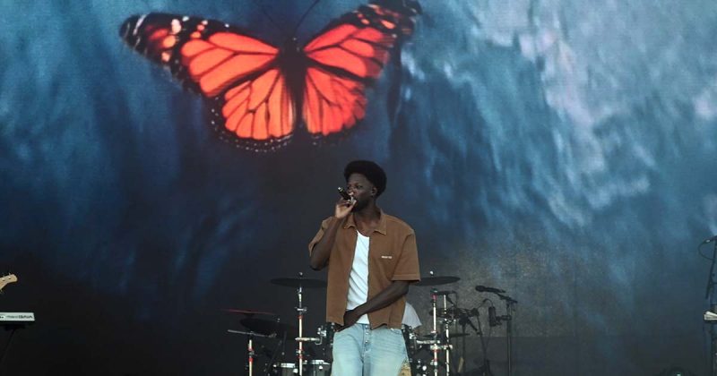 O cantor Papillon em palco no primeiro dia do Sol da Caparica com um cen&aacute;rio de fundo que exibe uma grande borboleta