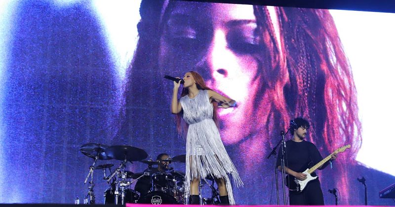 Plano aproximado da artista Ravyn Lenae a cantar ao microfone durante a jornada de s&aacute;bado do MEO Kalorama.