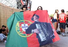 Último dia do Sol da Caparica encerra quatro dias de música em português Último dia do Sol da Caparica com público a segurar bandeira portuguesa com imagem de Quim Barreiros