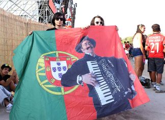 Último dia do Sol da Caparica encerra quatro dias de música em português Último dia do Sol da Caparica com público a segurar bandeira portuguesa com imagem de Quim Barreiros