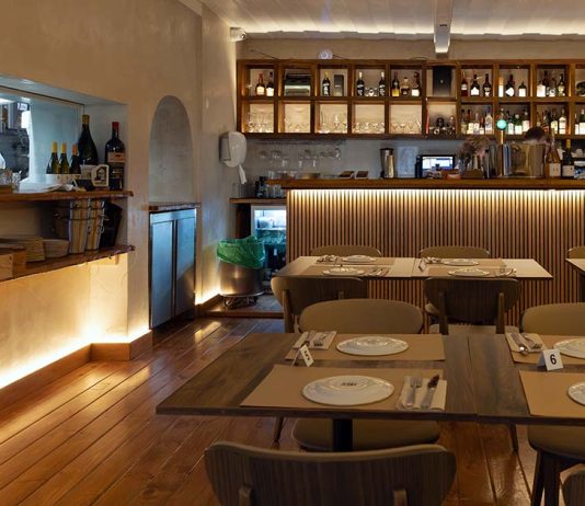 Restaurante Vizinhos do Rei cruza sabores e memória no coração de Odivelas Interior da sala de refeições do restaurante Vizinhos do Rei em Odivelas com mesas dispostas e balcão iluminado ao fundo